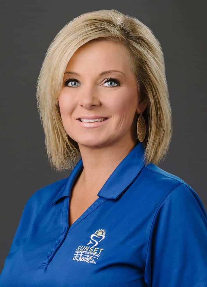 Head-and-shoulders portrait of a smiling blonde woman wearing a blue polo shirt with a logo.